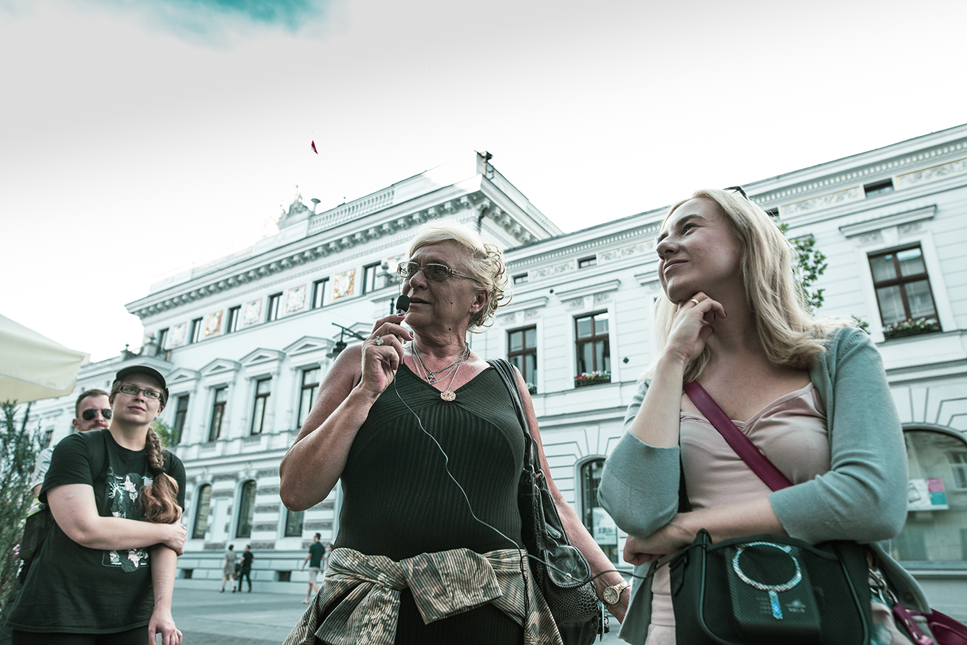 Trzy kobiety stoją pod Urzędem miasta Łodzi, jedna z mikrofonem, trwa spacer