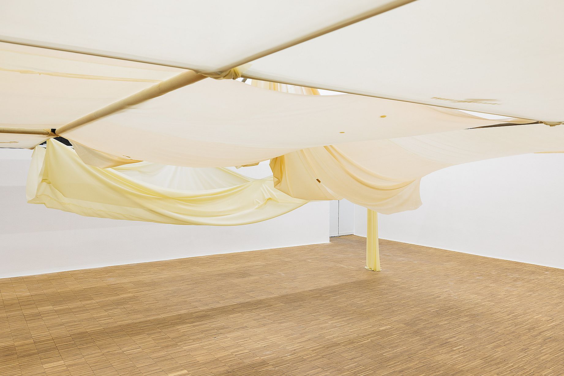 Duża materiałowa instalacja artystyczna, podwieszona pod sufitem galerii