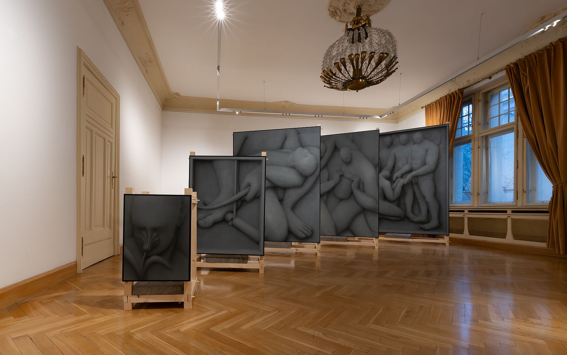 Instalacja artystyczna w galerii składa się z pięciu stojących, wielkoformatowych, czarno-białych paneli z nadrukowanymi zbliżeniami splecionych, nagich, ludzkich postaci w różnych pozach, zamontowanych na drewnianych stojakach i oświetlonych od góry.