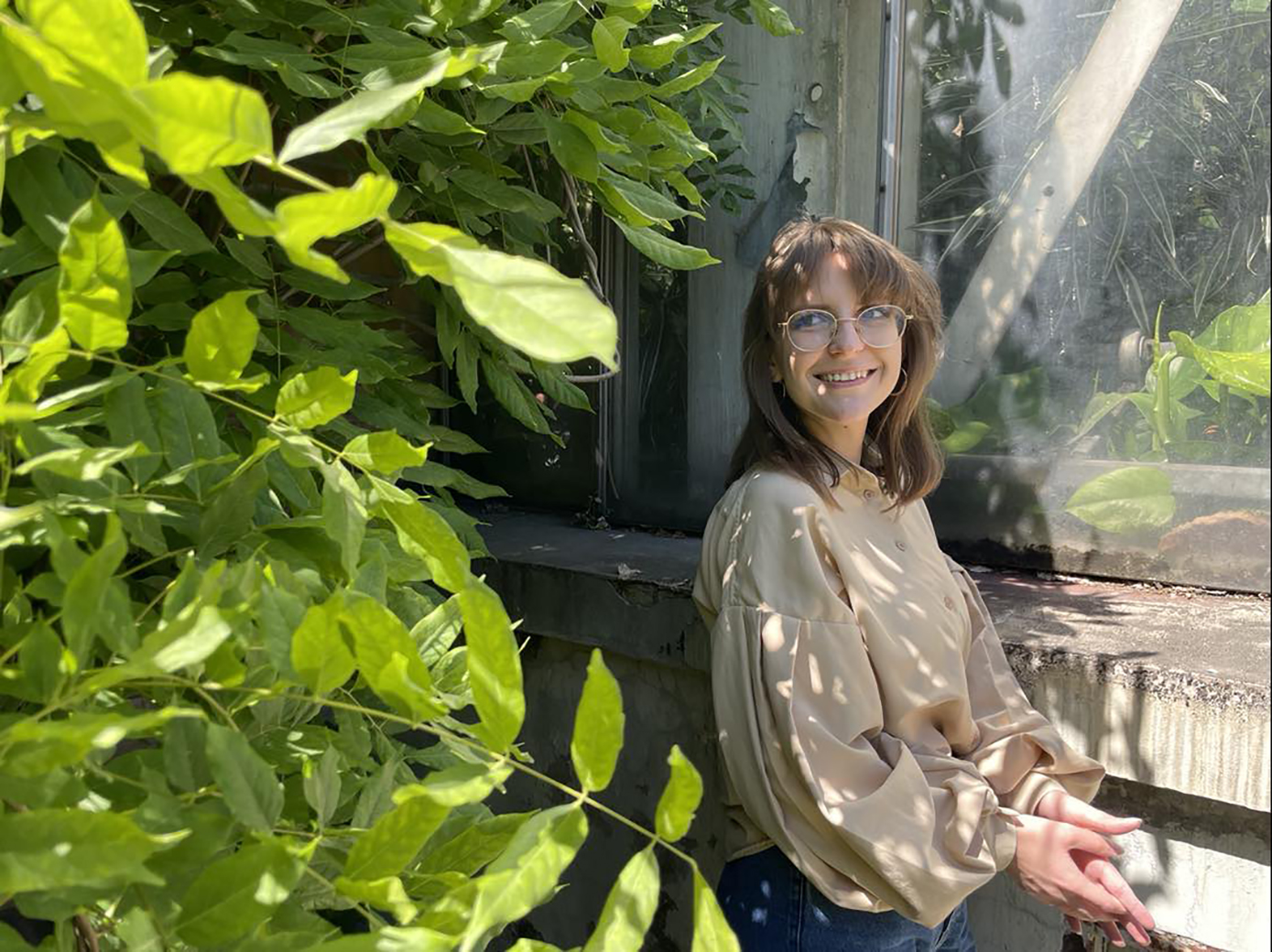 kobieta w okularach uśmiecha się, w tle dużo roślin