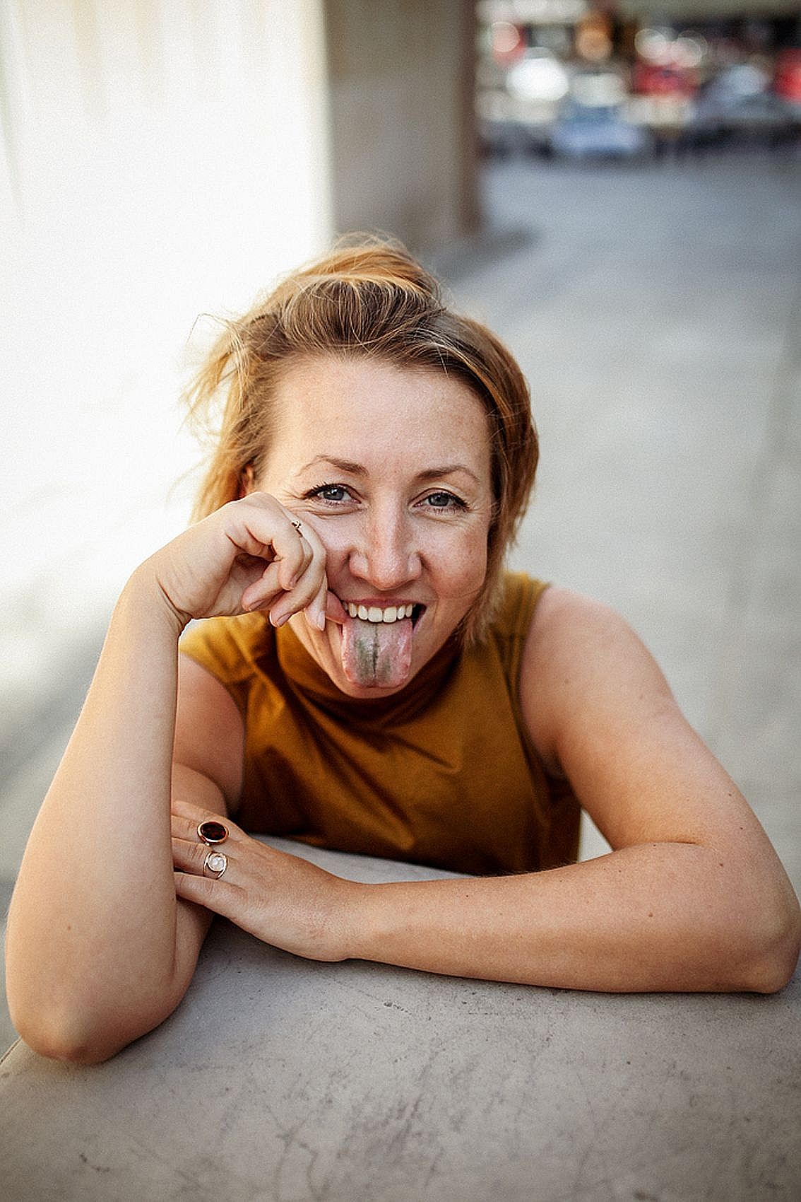 kobieta w żółtej koszulce na ramiączkach pokazuje język