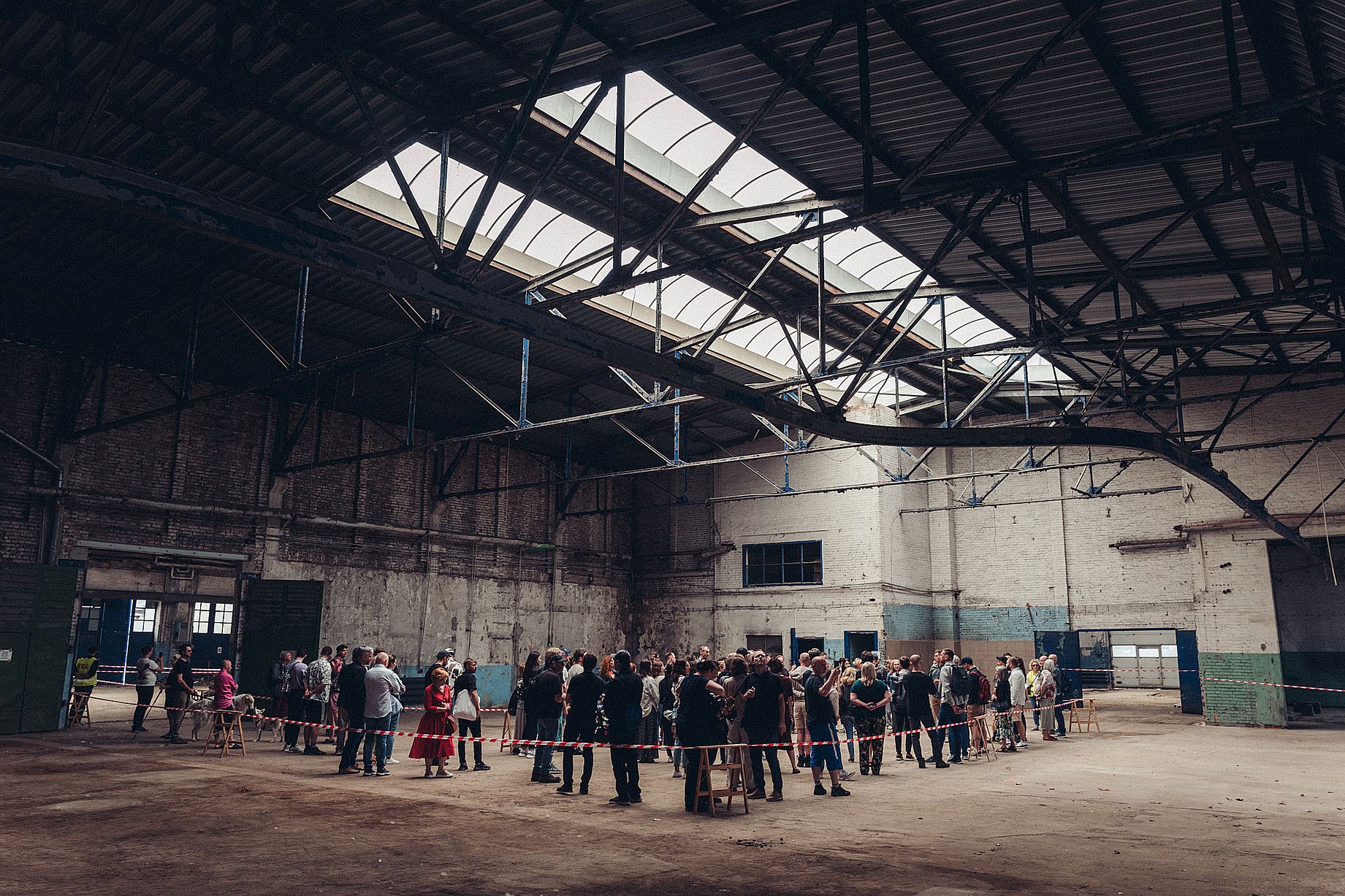 Zdjęcie wnętrza starej fabryki, na środku stoi grupa osób zwiedzjacych