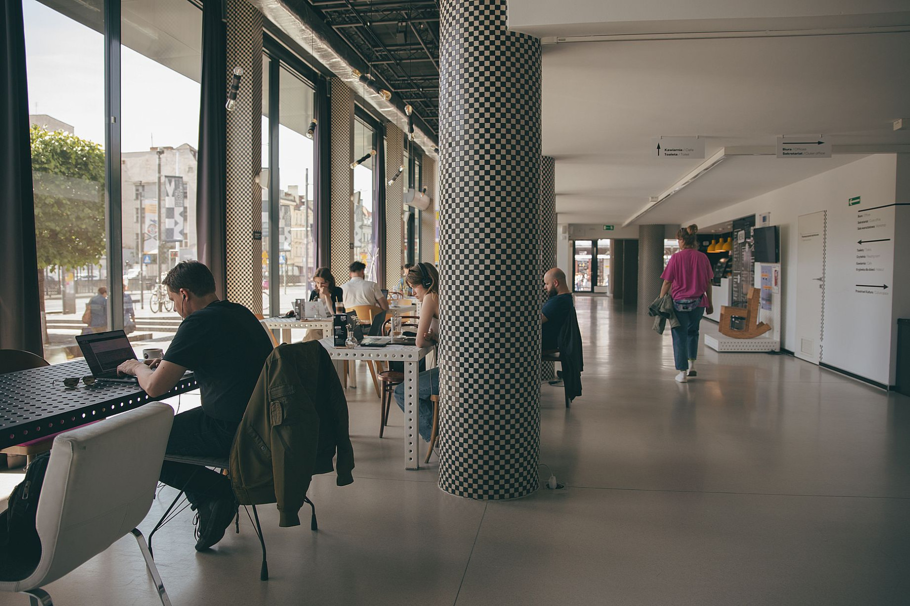 Jasne wnętrze z ślubami z mozaiką, część osób pracuje na laptopach